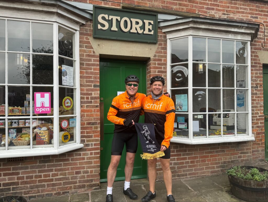 Steve Leicester (left) and Liam Carter (right) hold up the DHAN Foundation crest outside the Rochdale Pioneers Museum during the last phase of their charity cycle ride.